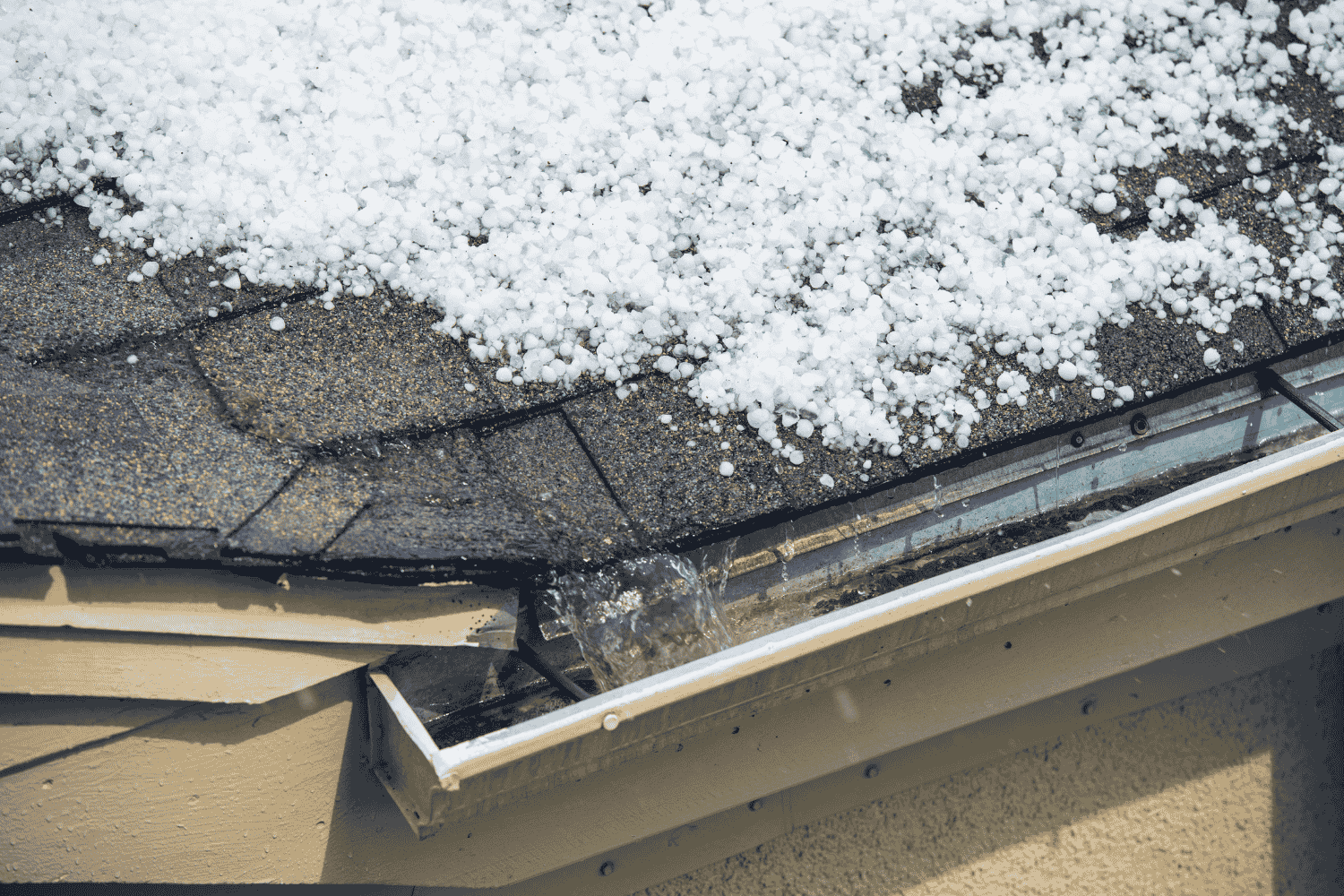 An overview of a property with signs of hail damage, including damaged siding and dented gutters.